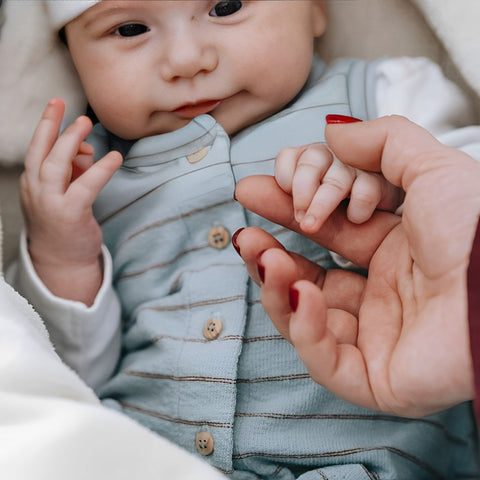 bébé qui tient la main de sa maman