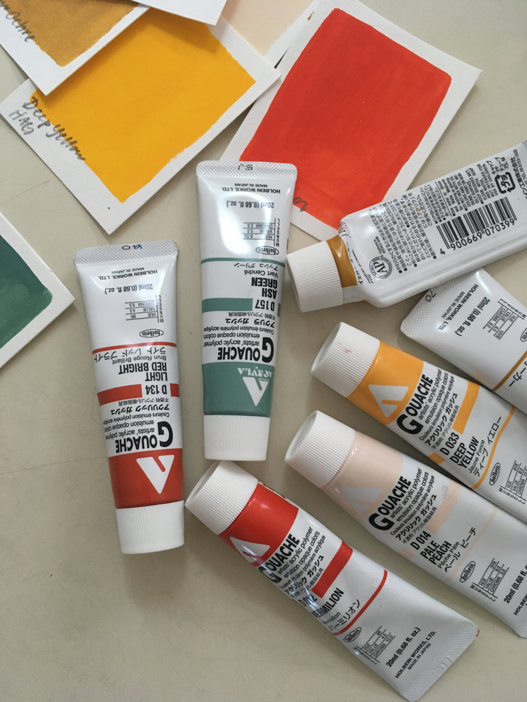 Photo of painting supplies including small tubes of bright and muted paint colors and small swatches of painted paper from paint tubes.