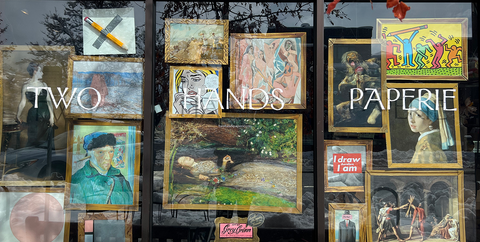 Two Hands Paperie Store window with gallery wall pencil artwork.