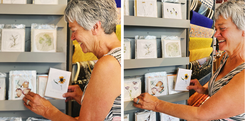 Denise with her cards placing them on the wall at Two Hands Paperie.