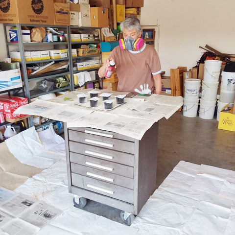 Denise using spray adhesive to mount her handmade paper onto her cards.