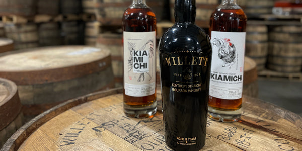 Bottles of Willett bourbon, including Willett Wheated Bourbon, on Willett barrels.