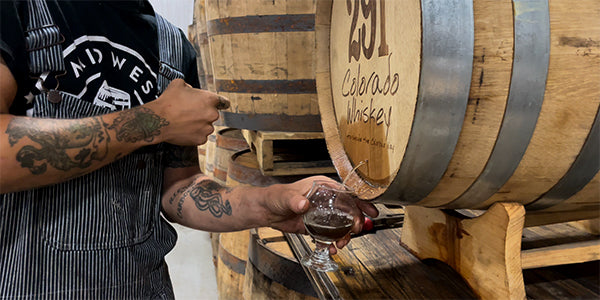 A Midwest Barrel Crew employee removed the Vinnie nail and is filling a small glass with a sample from the barrel.