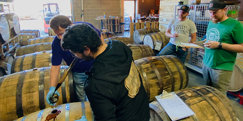 The Whiskey Hill and Midwest Barrel Co. teams pulling beer from barrels, tasting samples and taking notes.