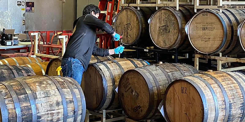 A brewer prepares to pull beer samples from a bourbon barrel at Whiskey Hill Brewing Company.