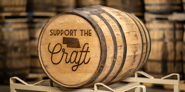 Engraved full size whiskey barrel on a rack with text Support the Craft and outline of state of Nebraska on the head