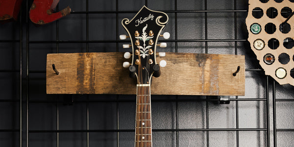 Whiskey barrel guitar stave hanger holding guitar on wall