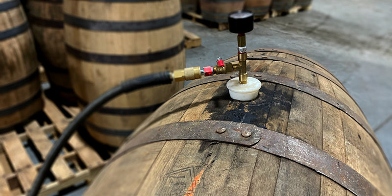 A pressure gauge connected to a bung in the hole of a whiskey barrel to check pressure