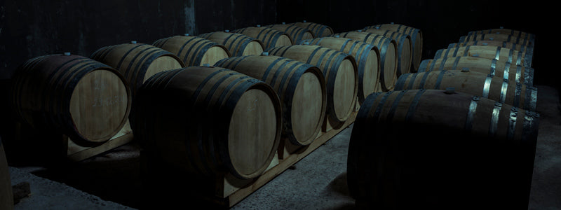 Barrels on barrel racks in a large, dark room