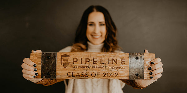 Midwest Barrel Co-Owner & President Jess Loseke holding a barrel stave engraved with Pipeline Entrepreneurs P and shield logo with text Pipeline A Fellowship of Great Entrepreneurs Class of 2022 