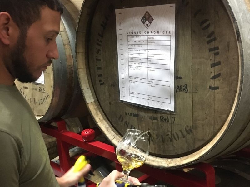 Zeke Peyton draws a sample of barrel-aged mead from a barrel at Superstition Meadery.