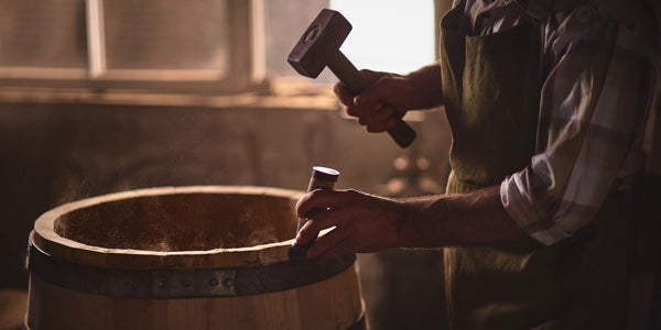 Cooper hammering a ring onto a barrel