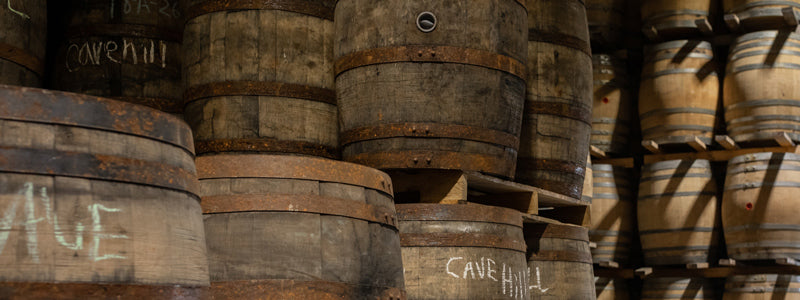 Used whiskey barrels on pallets stacked in a warehouse
