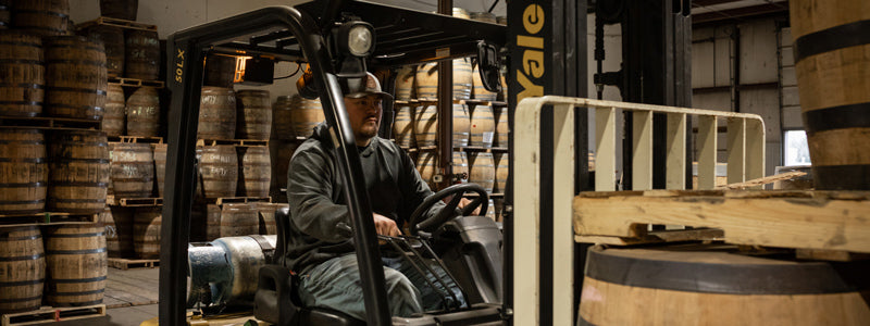 Worker operating a forklift in a Midwest Barrel Co. warehouse