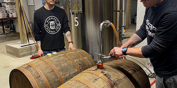 Brewer filling two used bourbon barrels in a small craft brewery
