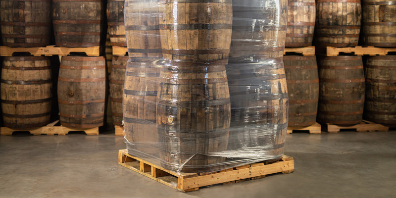 Used whiskey barrels for decor and furniture wrapped in plastic and loaded on a pallet