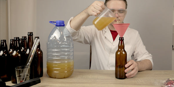 Homebrewer pouring beer from larger container into glass bottles