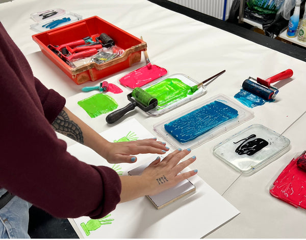 Textile Printing being taught by Rachel Anderson of Contrary to Reason, with pink, green and blue inks, using wooden blocks and rollers to create prints on Textiles.