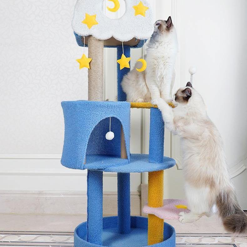 Three cats lounging in a cat tree with four levels. It has a sky theme with stars and clouds in the design making it more of a cat tree aesthetic