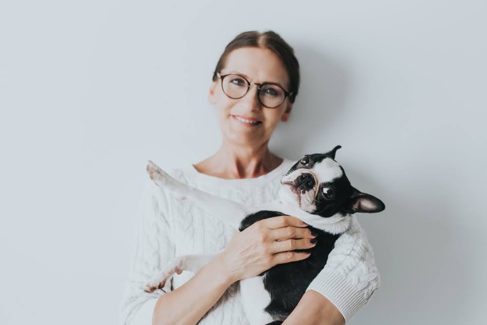 Woman smiling holding her Boston terrier