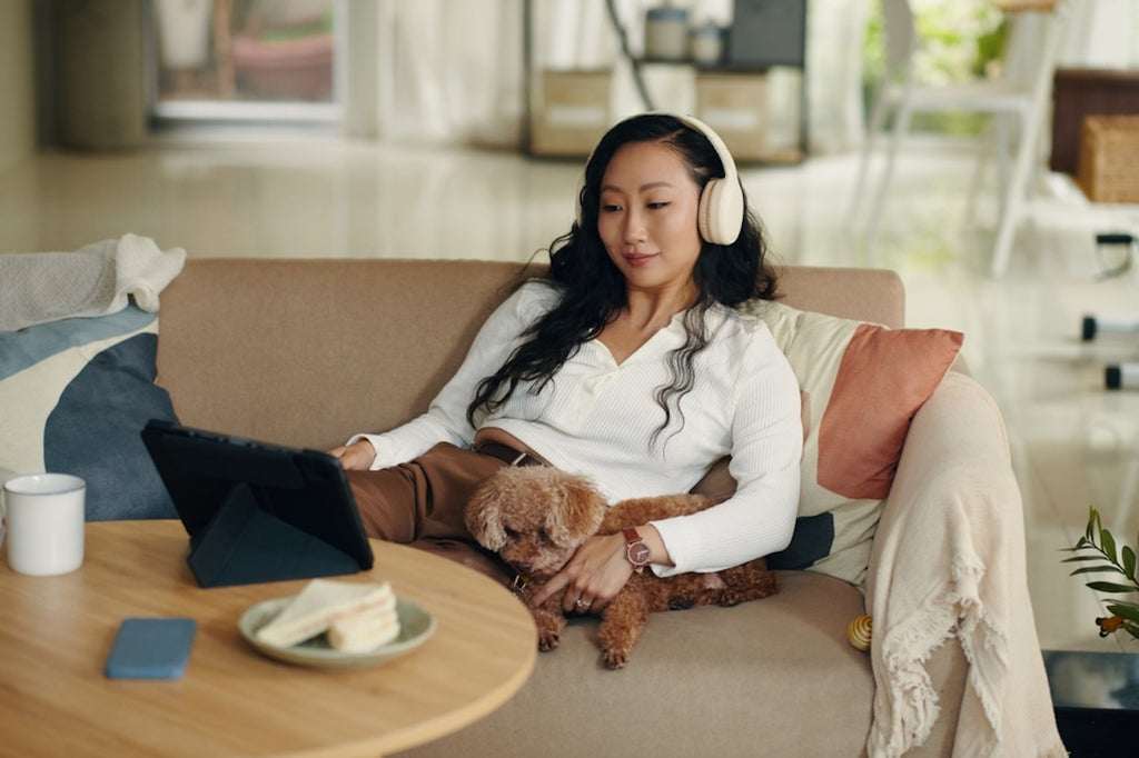 Young Asian woman looking at laptop with dog sitting next to her