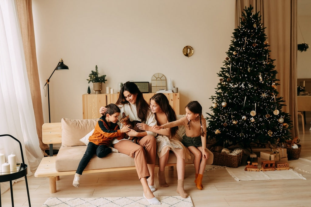 Mom, kids, and cat cuddling in front of Christmas tree