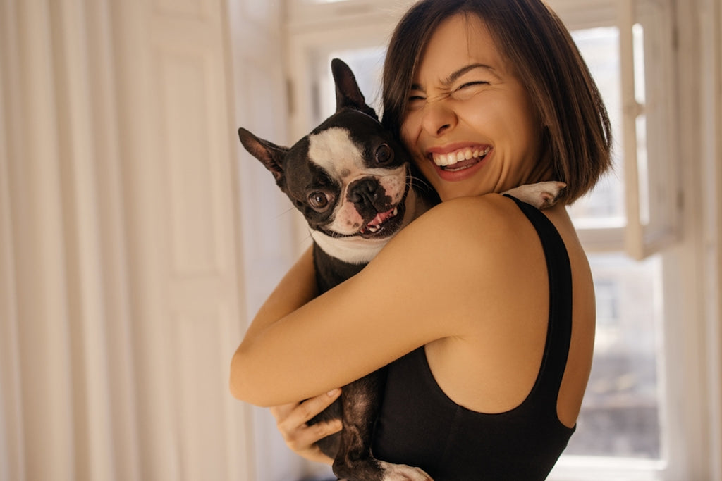 Woman smiling while holding her Boston terrier