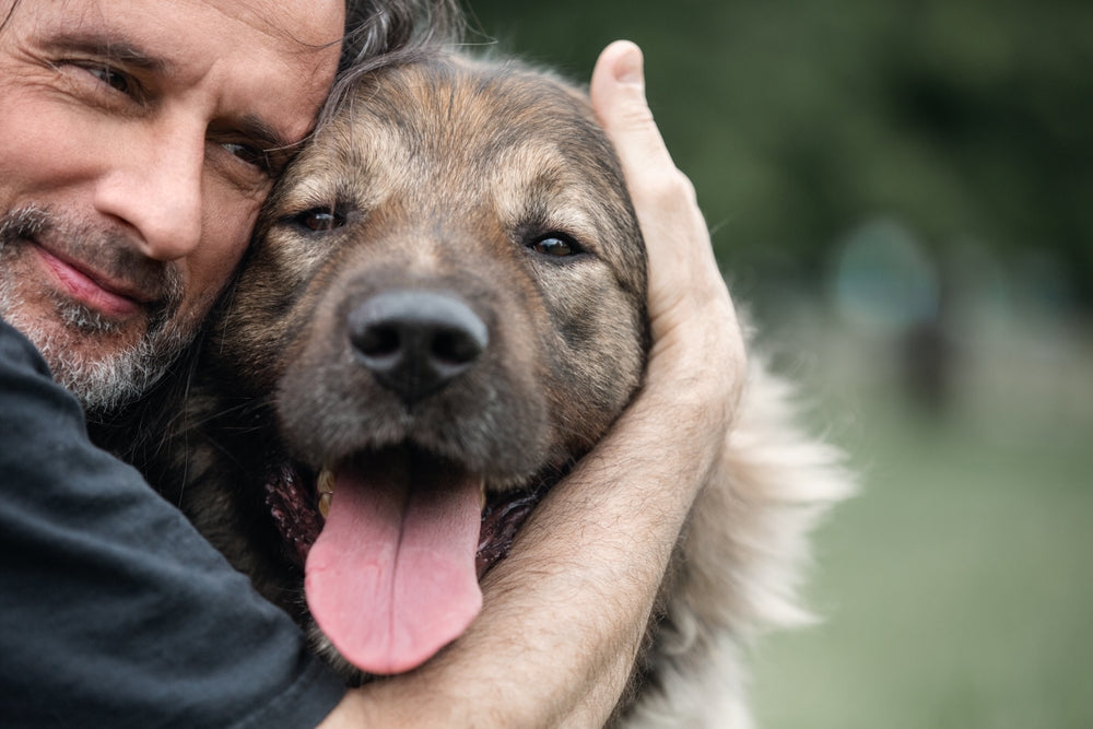 Middle aged man hugging his senior dog