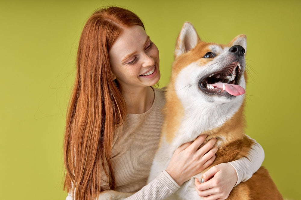 Redheaded woman smiling while holding dog