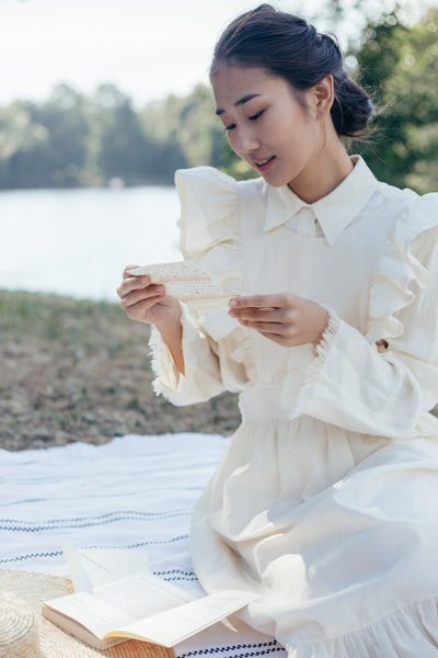 asian woman reading letter by lake