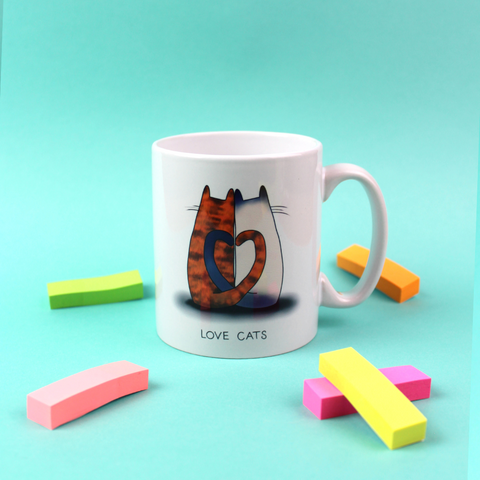 A mug is shown with an illustration of two cats with their tails entwined to make a heart shape above the words Love Cats.
