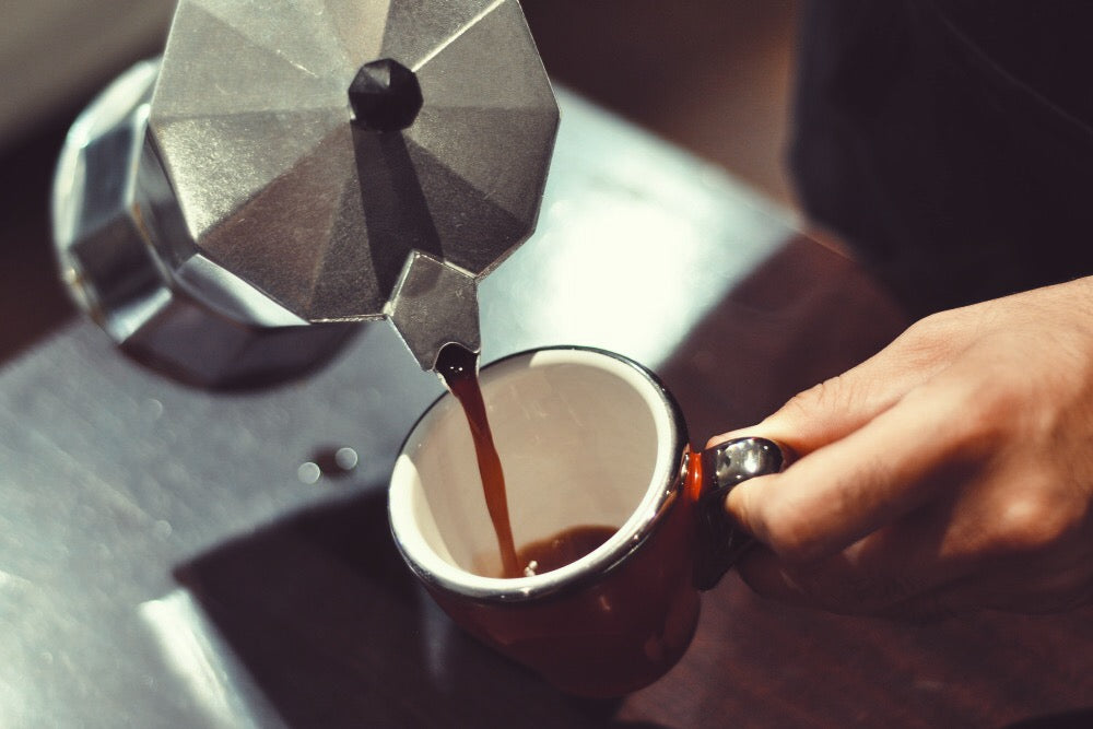image of moka pot pour a coffee in a cup
