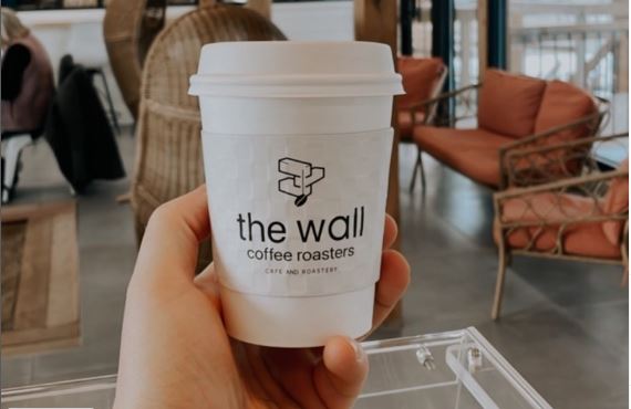 coffee in a disposable cup with "the wall" brand printed on it