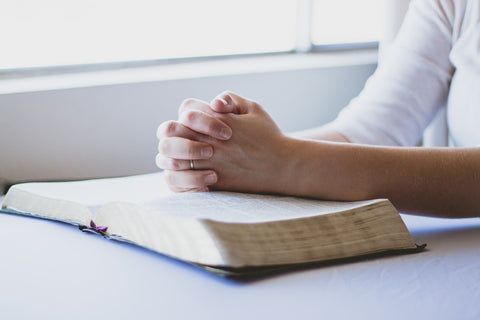 An Intentional Christian lifestyle - praying hands held over an open bible