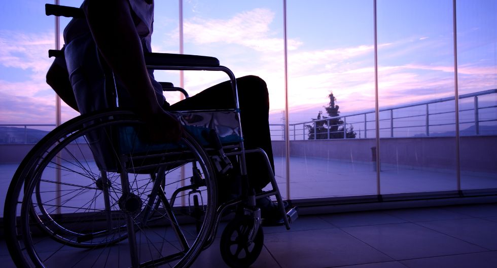 ragazzo su sedia a rotelle guarda un cielo azzurro e rosa come metafora dell'importanza della sessualità nella disabilità