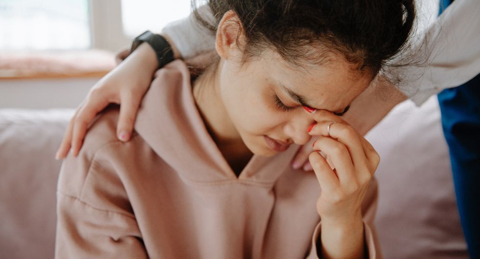 donna sconsolata a causa delle difficoltà nel venire viene confortata con due mani sulle spalle