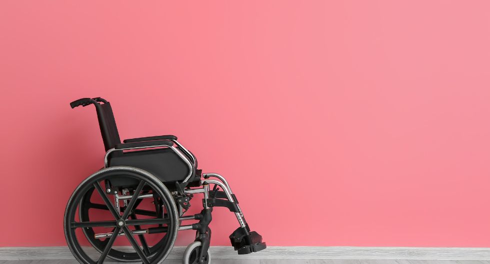 sedia a rotelle vuota su sfondo rosa come simbolo che questo oggetto non deve essere condizionante della sessualità di un paraplegico