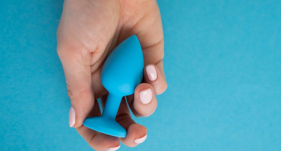 anal plug azzurro tenuto in una mano uno dei sex toys di coppia più diffusi