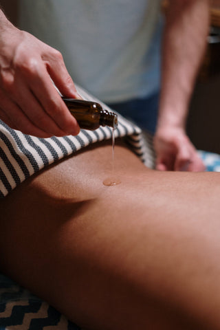 Person receiving CBD massage with oil on lower back.