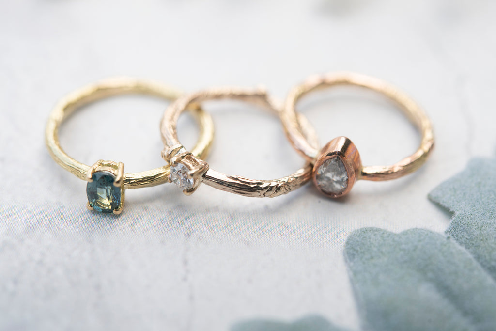 Gold twig engagement rings with green sapphire, white diamond and salt & pepper diamonds