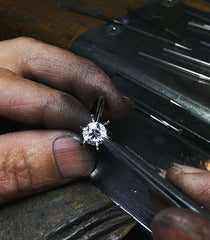 A jeweller setting a round brilliant cut diamond into an engagement ring