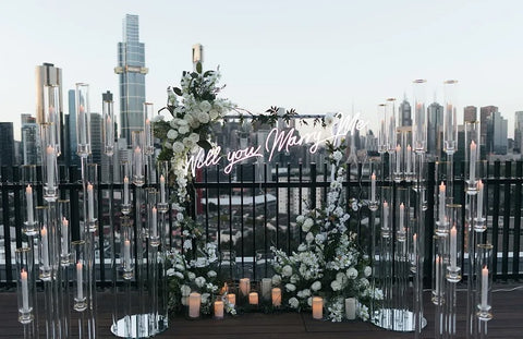 Rooftop view of the Melbourne city skyline with a lovely floral proposal arrangement and a marry me sign displayed with candles surrounding