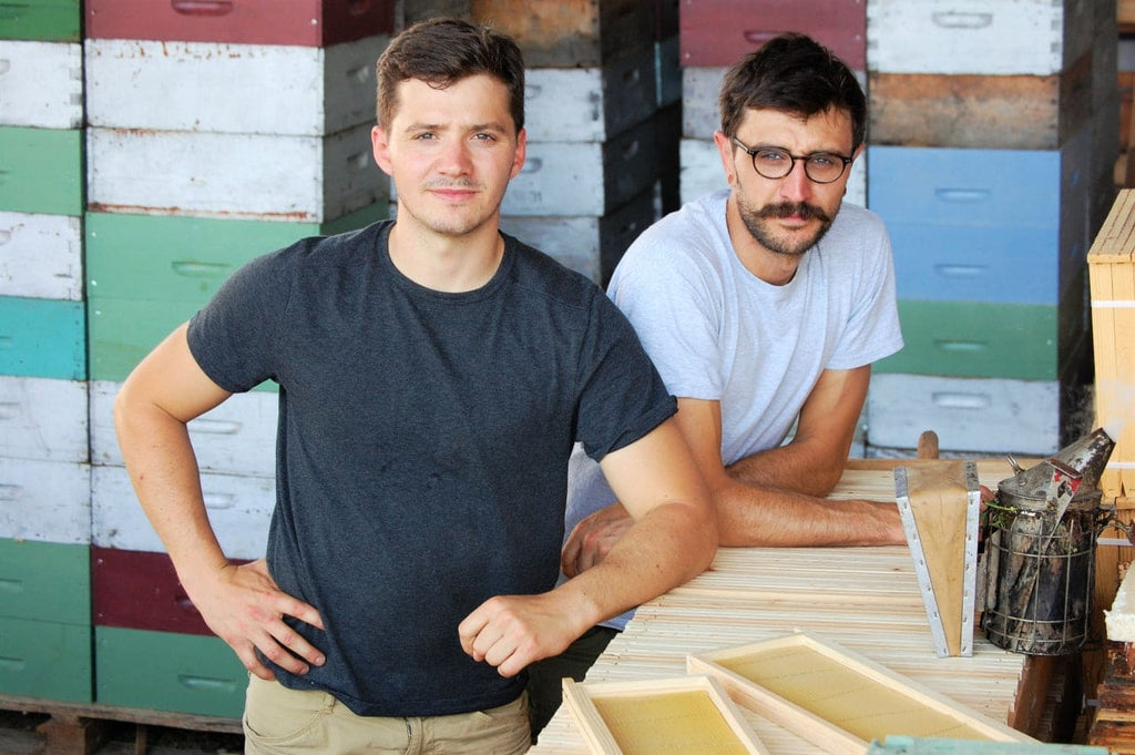 Deux producteurs souriants acoudés à un comptoir