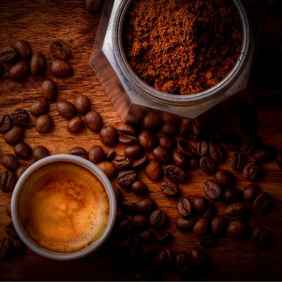 A cup of coffee surrounded by a bag of coffee beans 