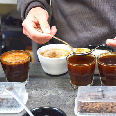 Person learning how to make a professional cup of coffee, using spoons to measure and transfer the milk