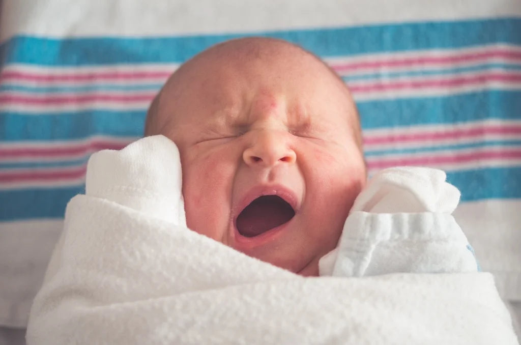 baby sleeping and yawning with a sleep sack on