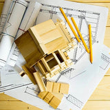 wooden house model on top of floor plan papers