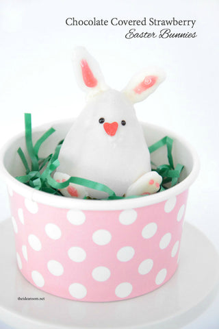 White chocolate covered strawberry in the shape of a bunny sitting in a nest of green in a small cup