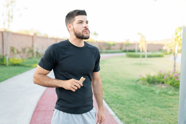 An athlete eating a low sodium protein bar after exercising