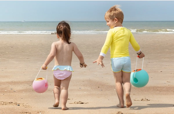 Deux enfants jouant à la plage avec Quut Toys en mains.
